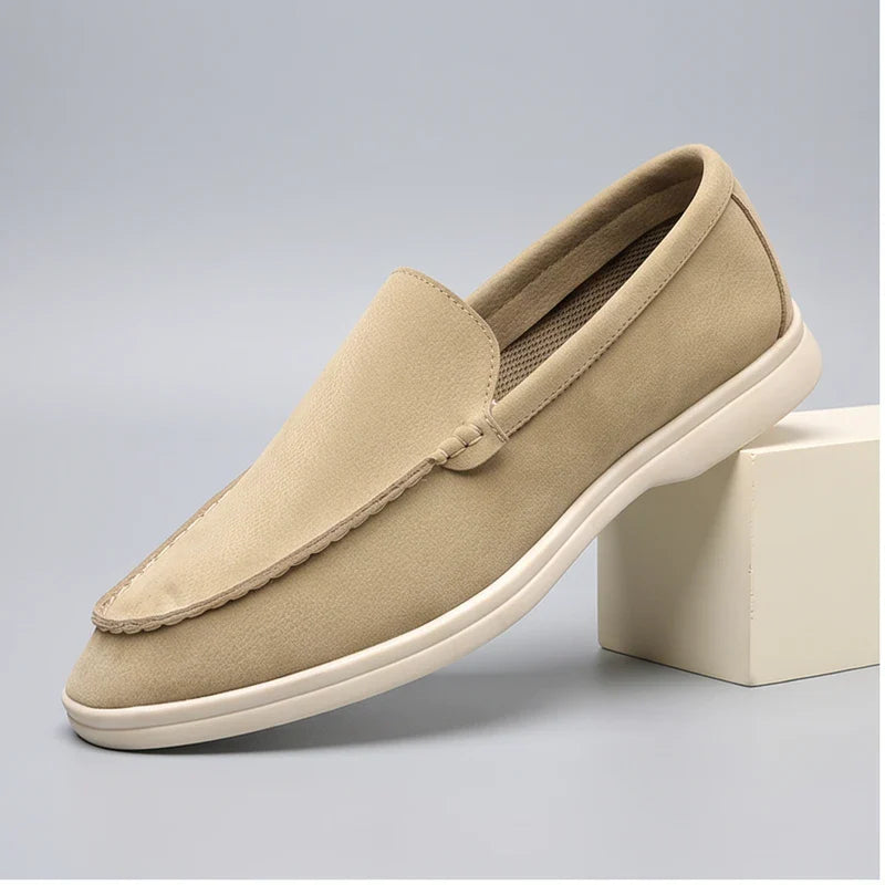 Beige suede loafers in a studio background