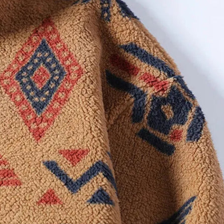 Close-up of a textured fabric with geometric patterns in red, blue, and black on a beige background.