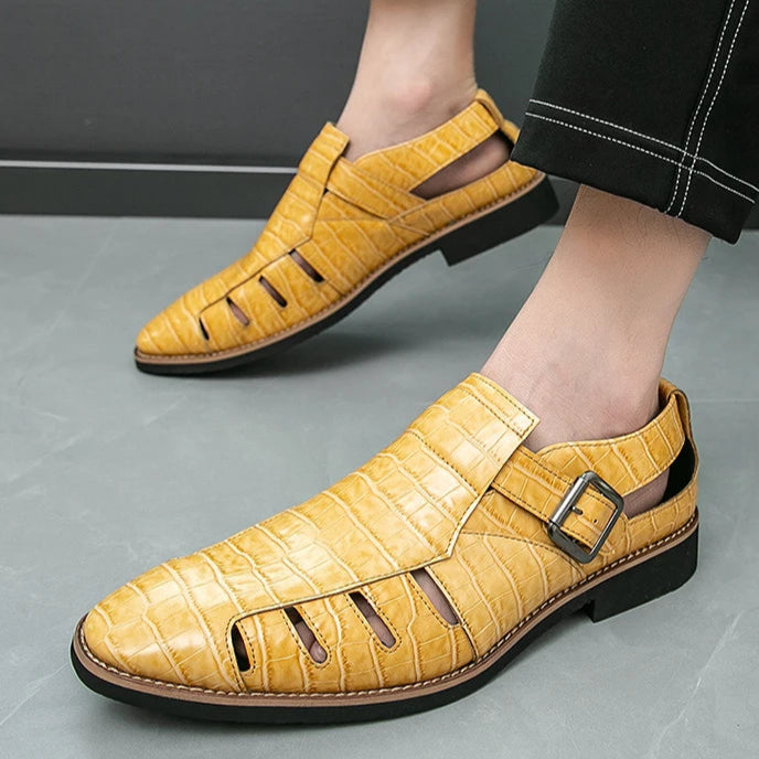 Yellow sandals worn with black pants on a gray floor.