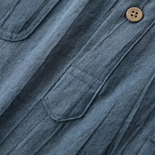 Close-up of a blue denim shirt with a button on a white background