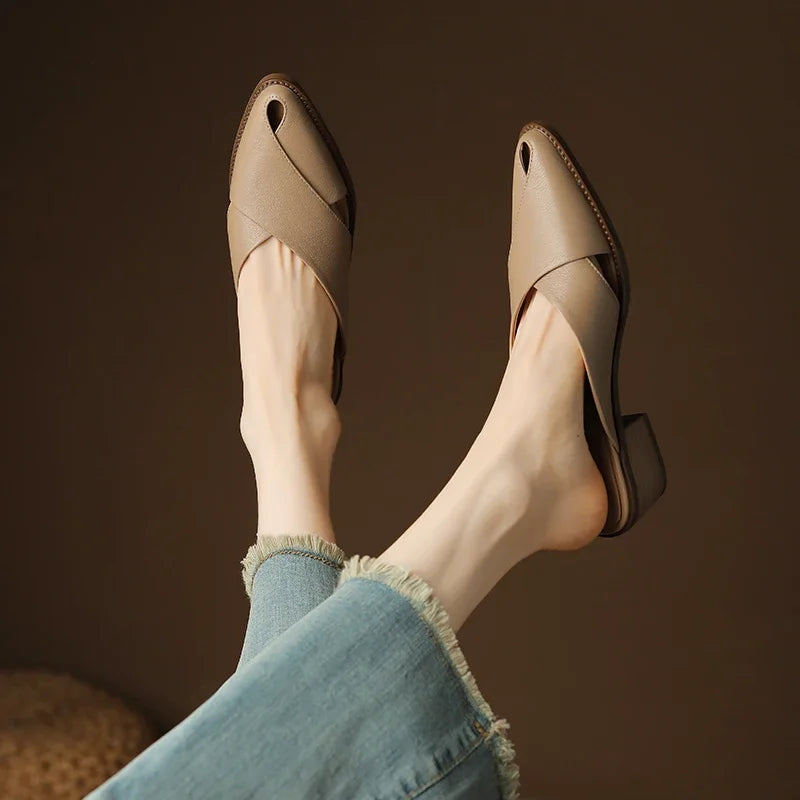 Beige open-toe shoes worn with light blue jeans against a brown background
