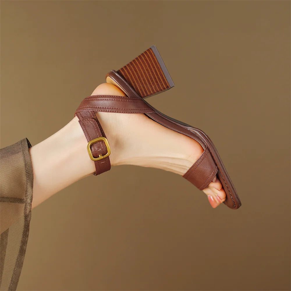 Brown sandal with a gold buckle on a beige background
