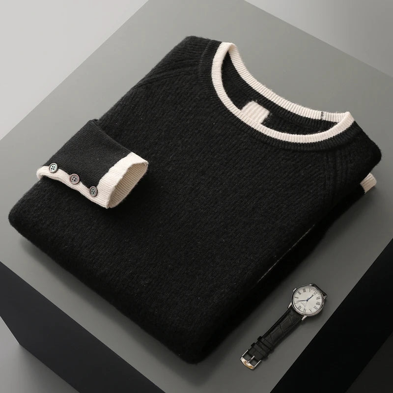 Black sweater with white trim on a gray surface, accompanied by a black watch.