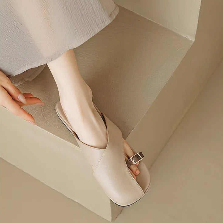 Beige open-toe shoes worn by a person on a neutral background
