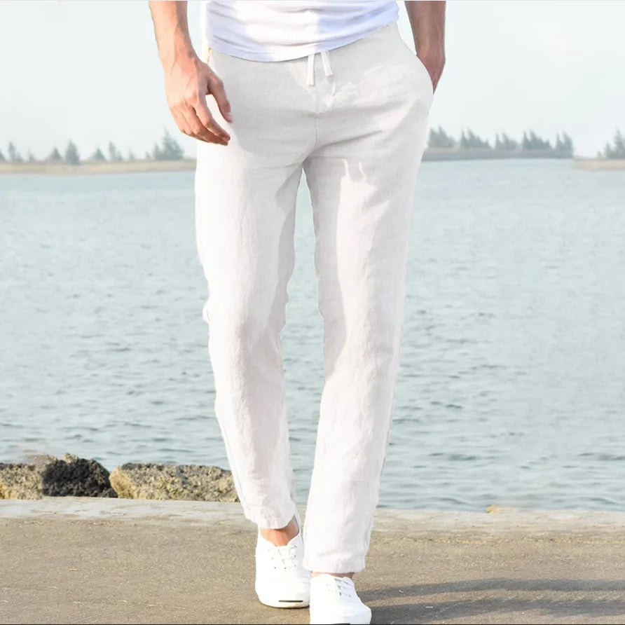 Men's white linen trousers with a drawstring waist and relaxed fit.