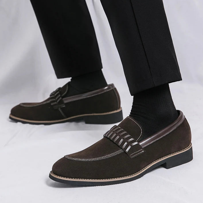 Brown loafers worn with black pants on a light gray background