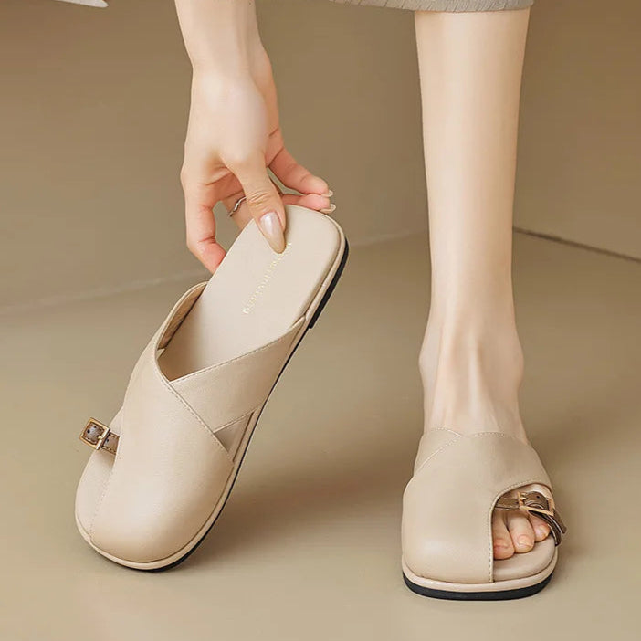 Beige open-toe shoes worn by a person on a beige background