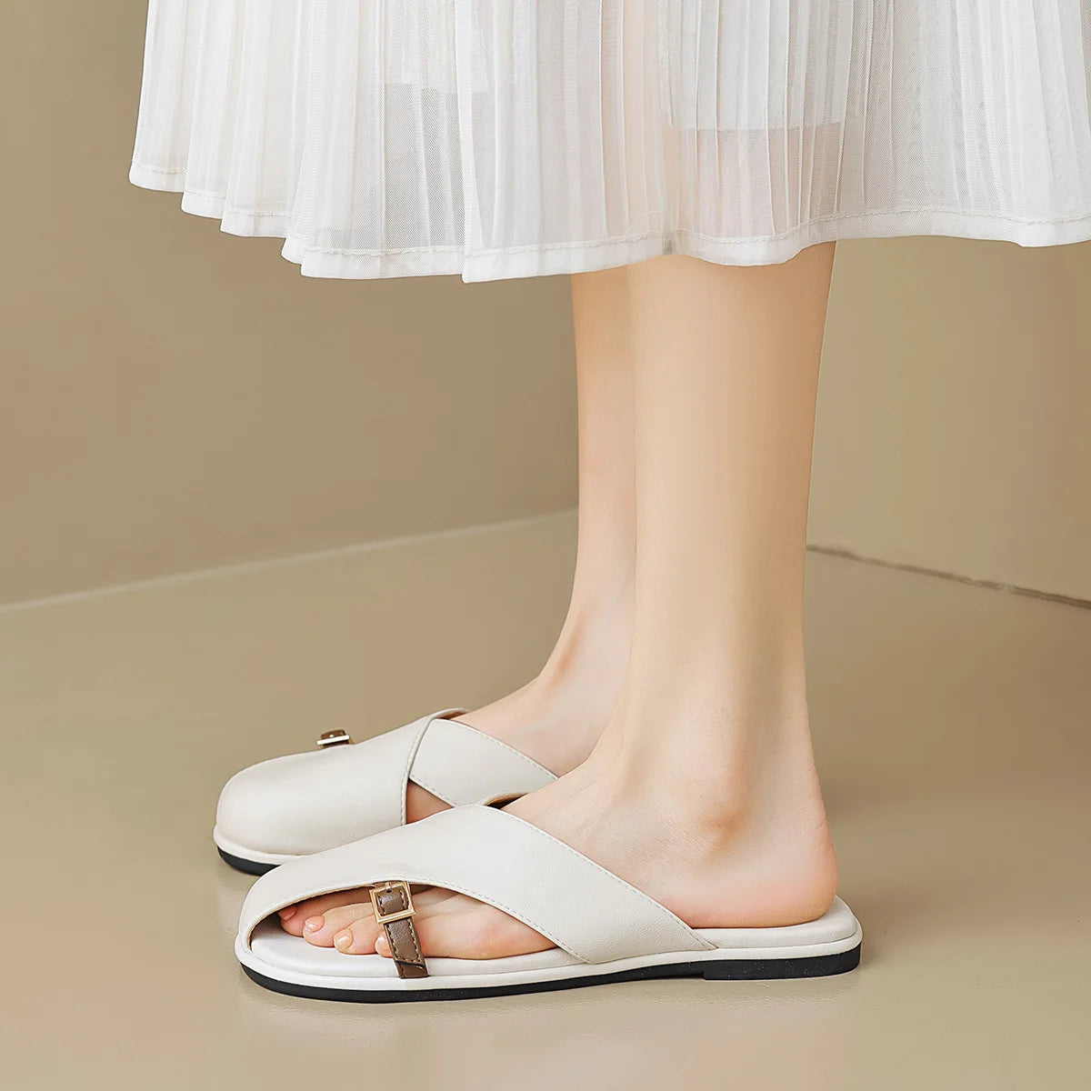 White sandals worn with a white skirt on a beige background