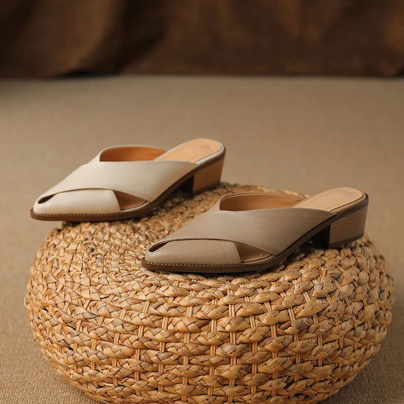 Pair of beige sandals on a woven mat with a blurred brown background