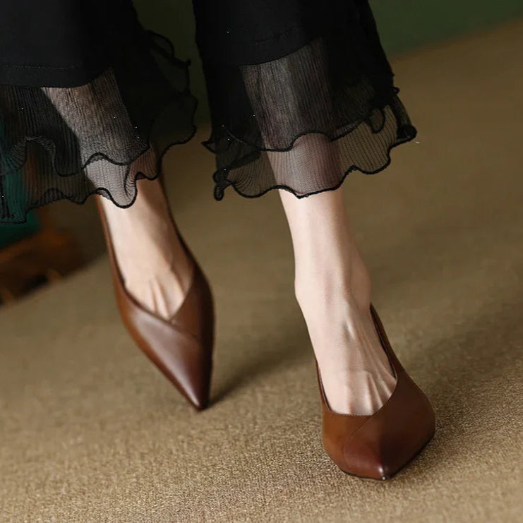 Brown shoes worn with a black skirt on a beige carpet