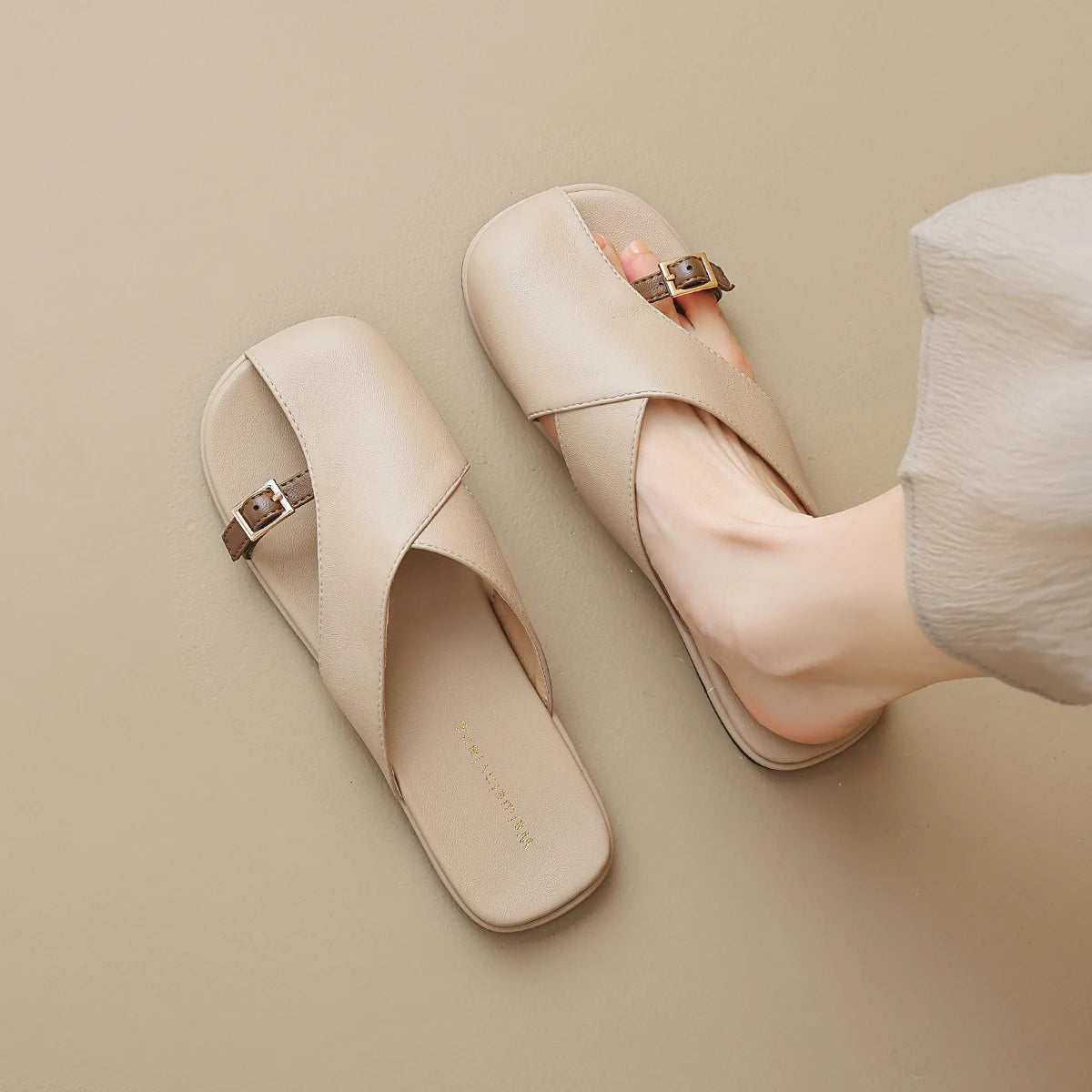 Beige sandals with gold buckles on a beige background
