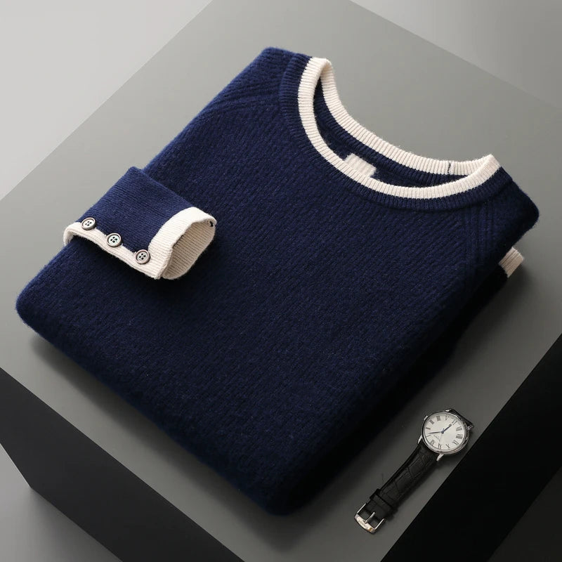 Folded navy blue sweater with white trim on a gray surface, next to a watch.