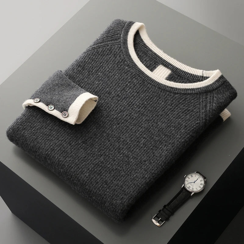 Folded gray sweater with white trim on a dark surface next to a watch.