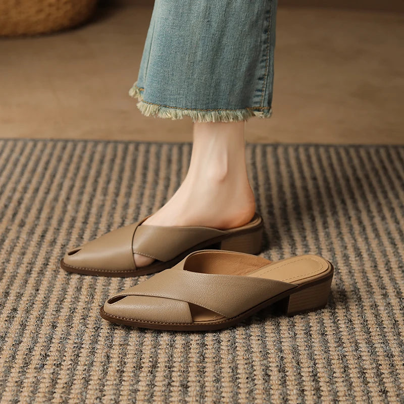 Brown sandals worn with light blue jeans on a striped rug.