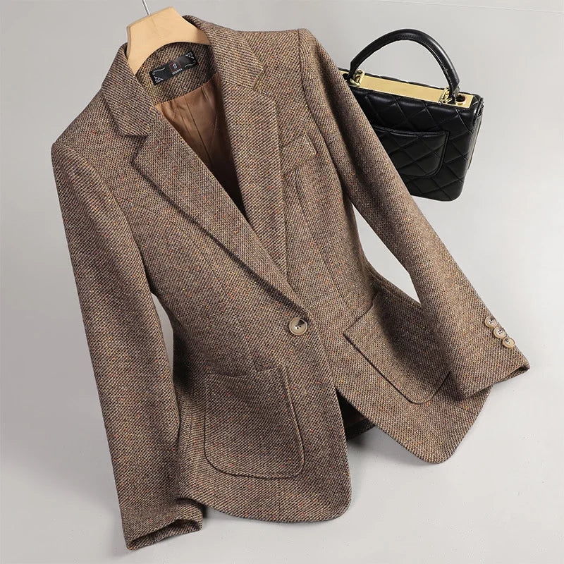 Brown blazer on a mannequin with a black handbag on a light gray background