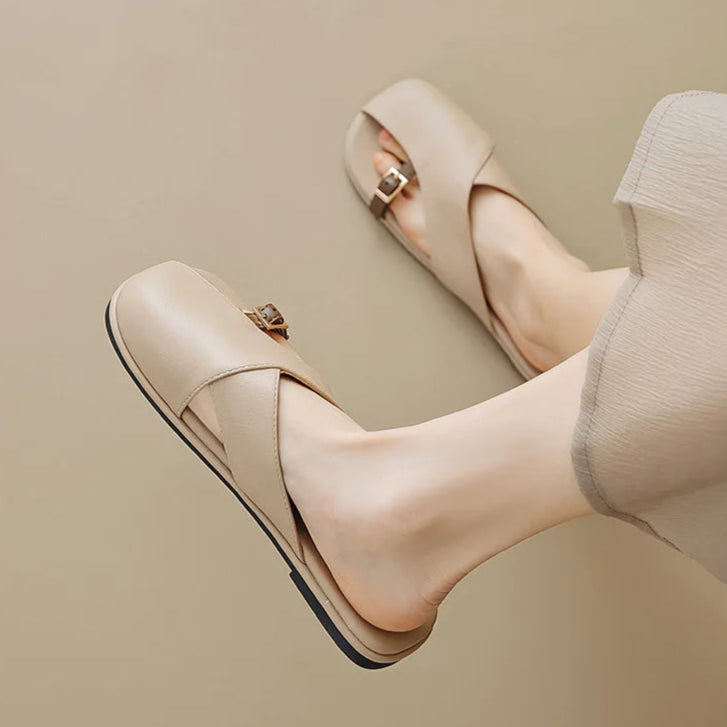 Beige high-heeled shoes being worn on a plain background