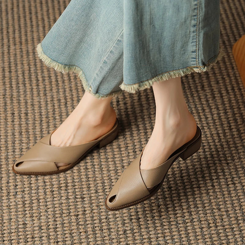 Person wearing beige open-toe shoes and blue jeans on a textured carpet.
