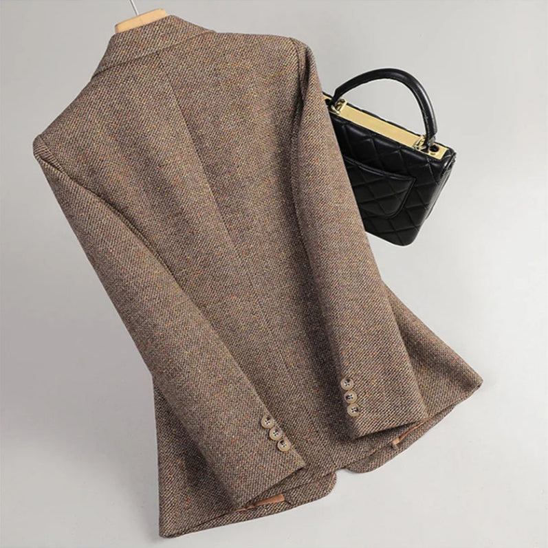 Brown blazer on a mannequin with a black handbag on a light gray background
