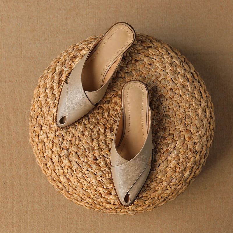 Pair of beige pointed-toe shoes on a woven mat with a brown background
