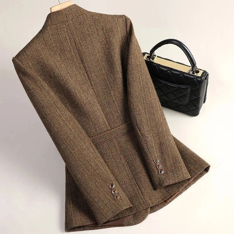Brown blazer on a mannequin with a black handbag on a light background